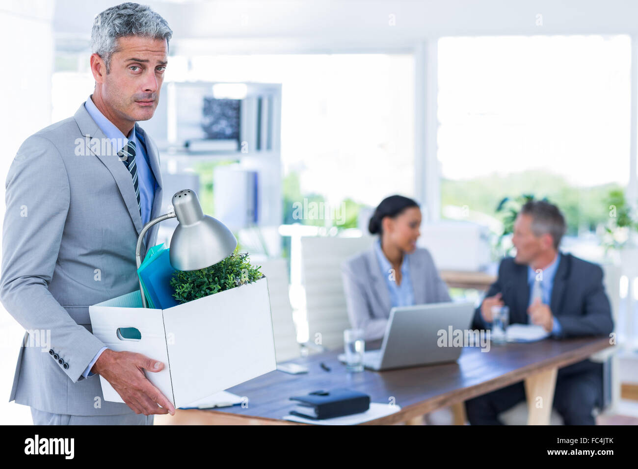 Businessman holding box with his colleagues behind him Stock Photo - Alamy