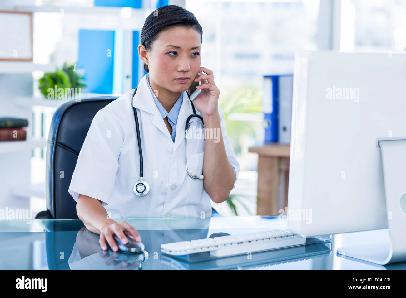 Concentrated doctor having phone call and using her computer Stock ...