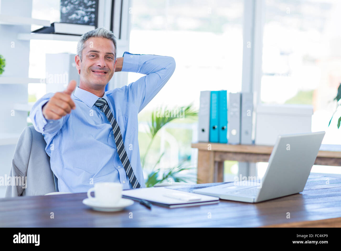 Happy businessman looking at camera with thumbs up Stock Photo - Alamy