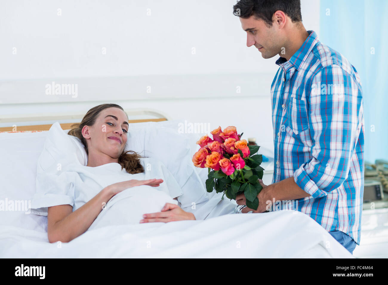 Man offering flowers to pregnant woman in hospital Stock Photo Alamy