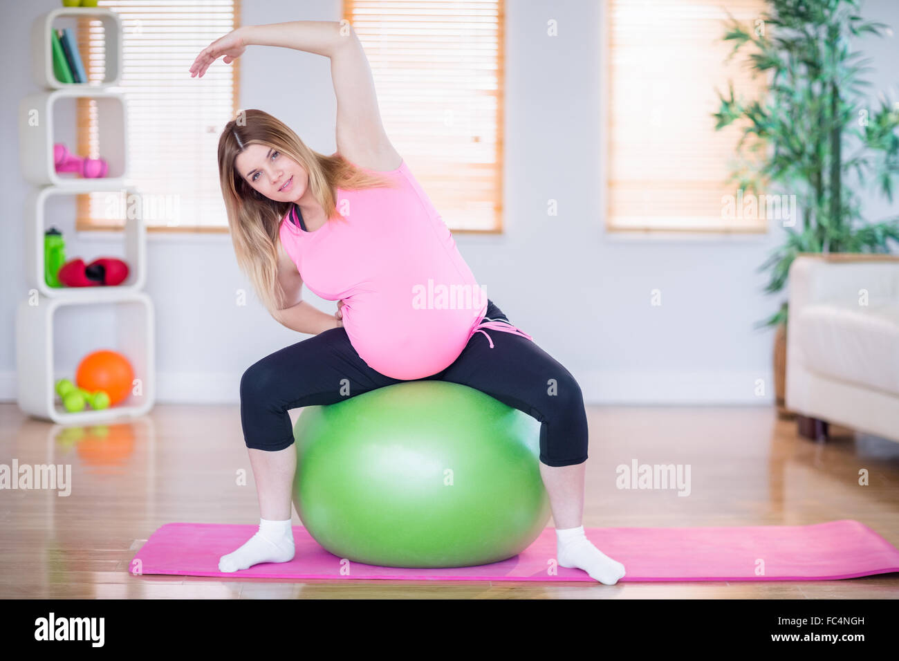 Pregnant woman looking at camera sitting on exercise ball Stock Photo ...