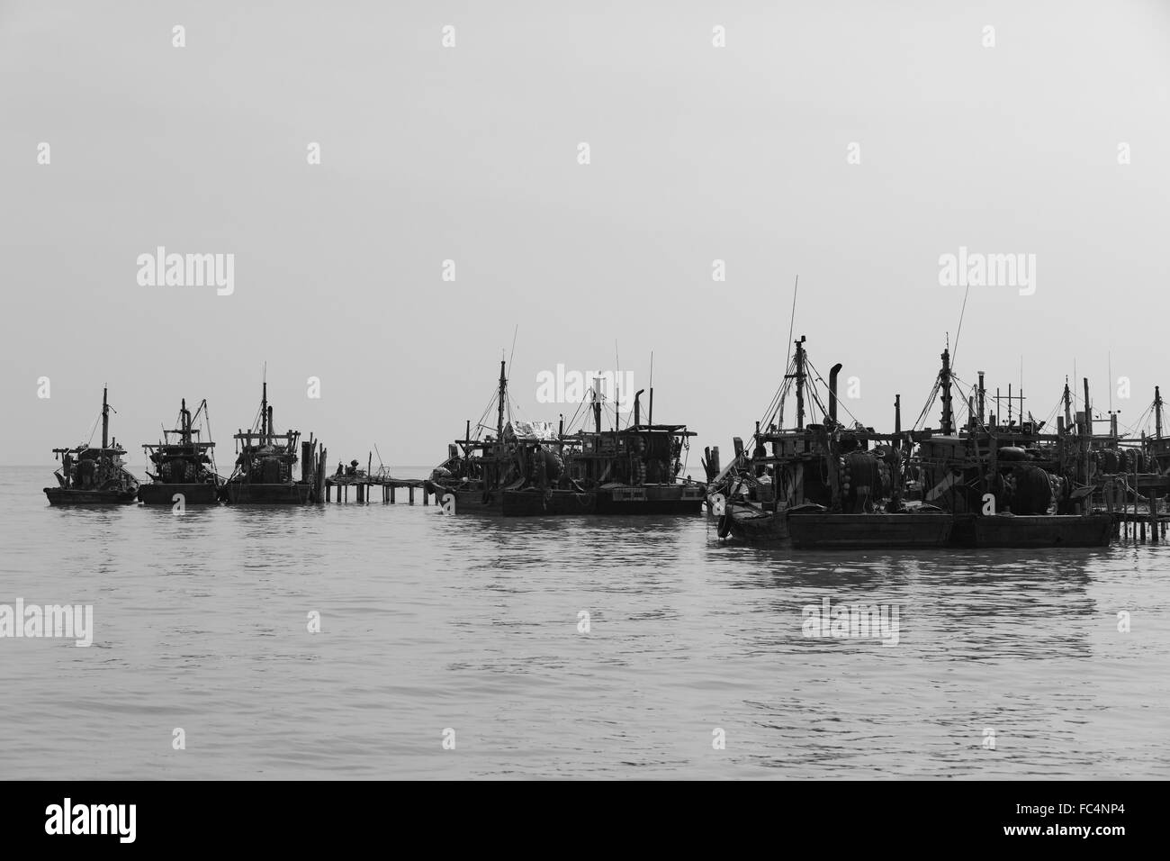 Monochrome collection of fishing boats alongside an old jetty at Teluk Bahang in Penang Malaysia. Stock Photo