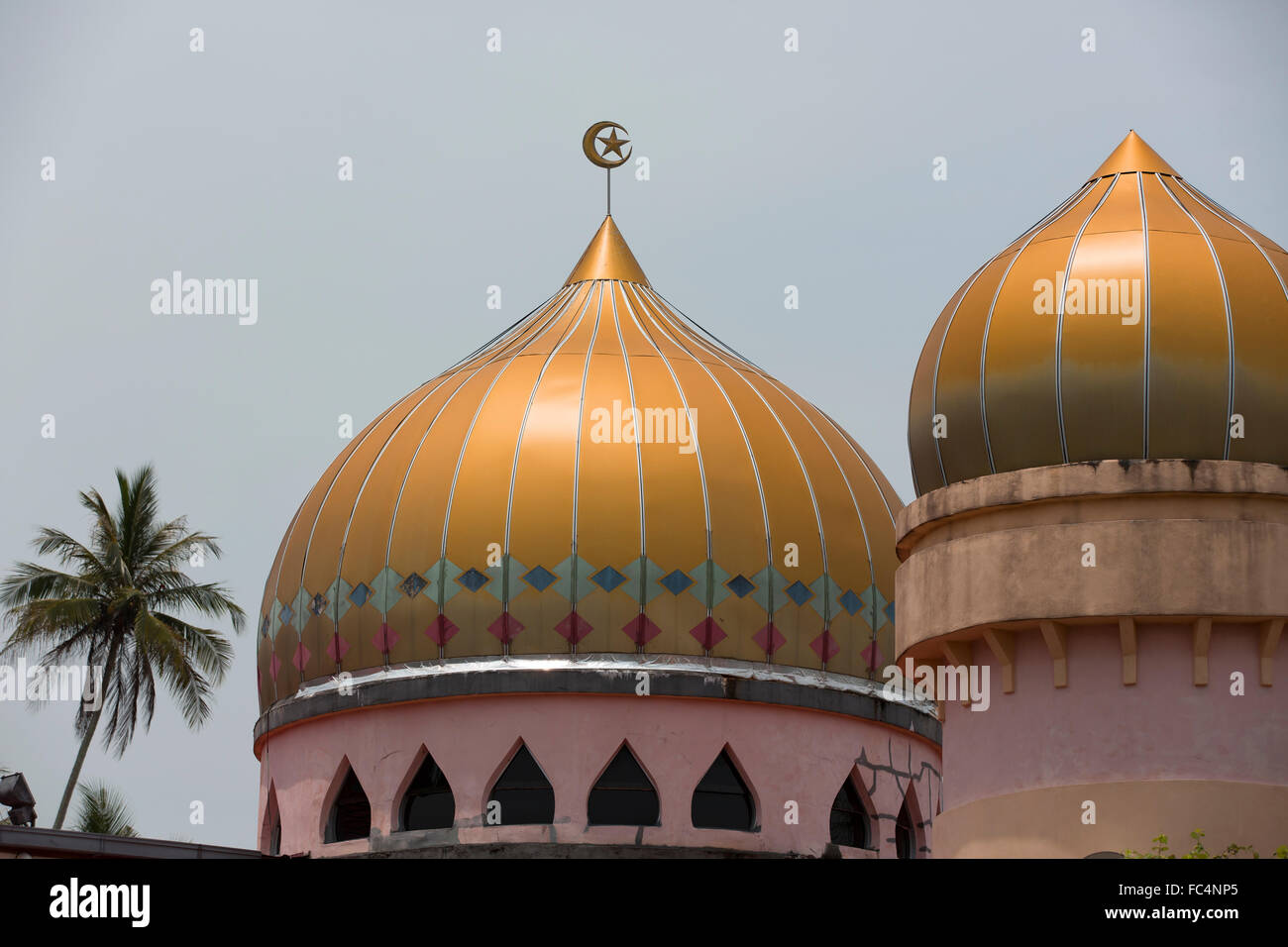 Two golden domes, Colorful tops to a Mosque located in Balik Pulau Penang. Large gold dome capped with moon and crescent. Stock Photo