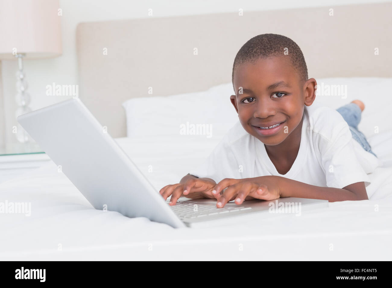 Portrait of a pretty little boy using laptop in bed Stock Photo - Alamy
