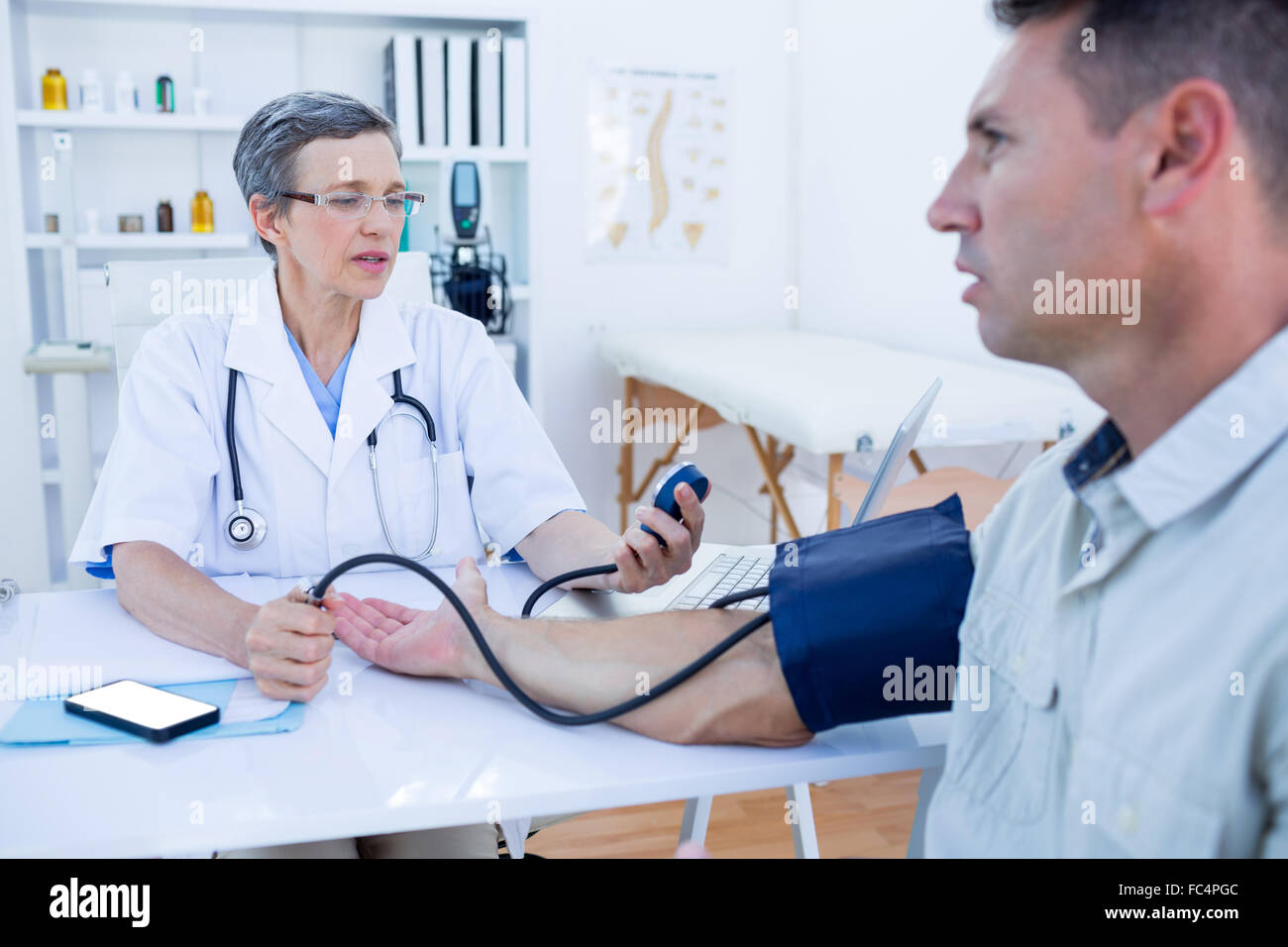 Doctor checking blood pressure of her patient Stock Photo