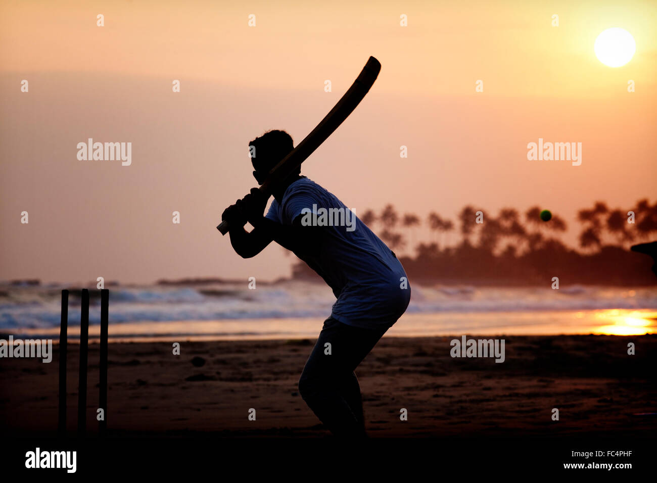 Boy playing cricket at sunset on tropical beach in Sri Lanka Stock Photo