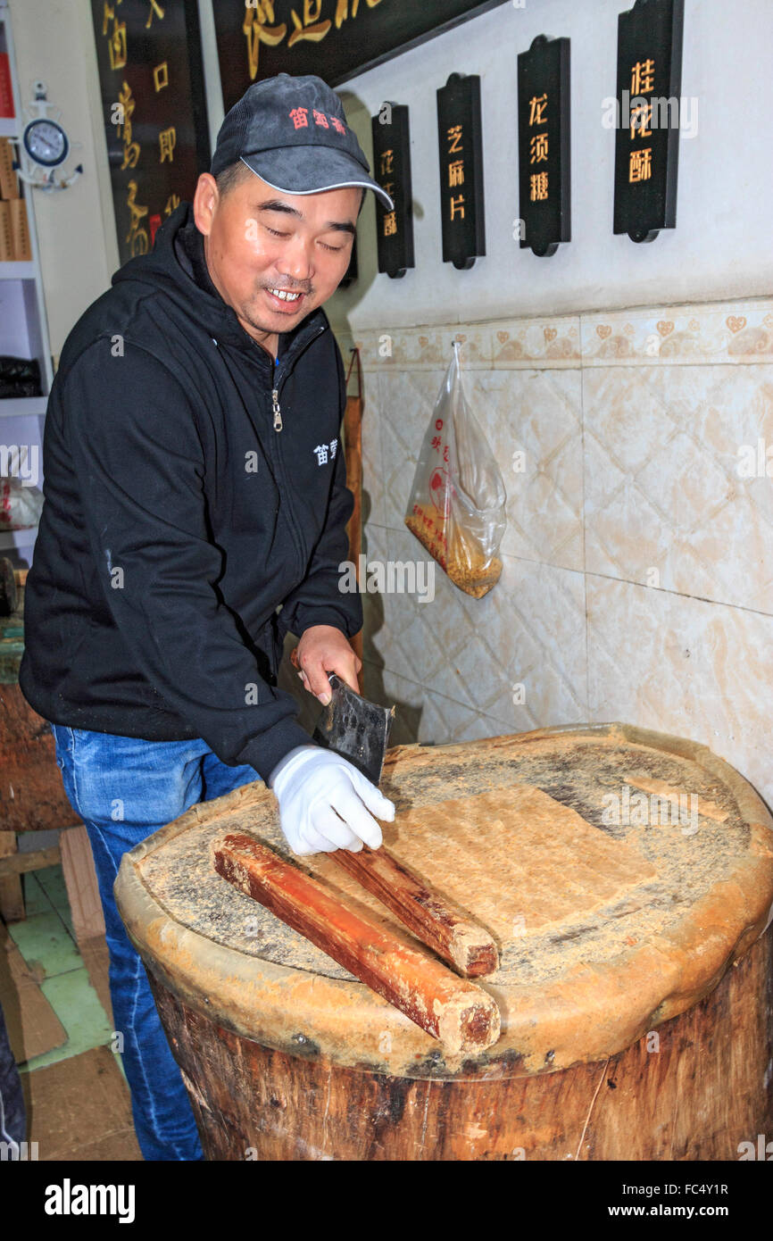 Men pound sesame seeds into flat paste which is then made into candy in a shop along Qinghefang Ancient Street, Hangzhou, China Stock Photo