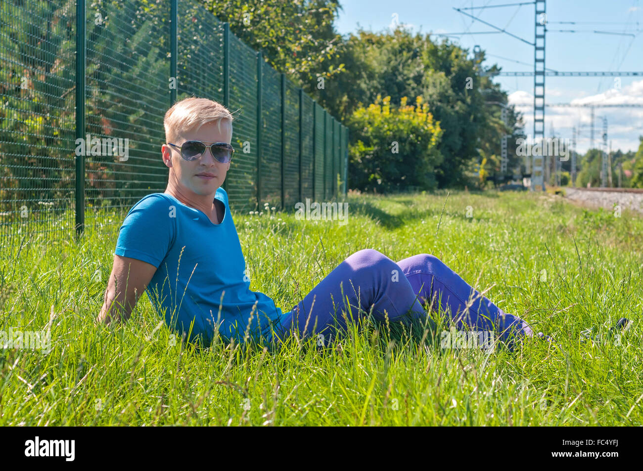 Young stylish man lying on the green grass Stock Photo
