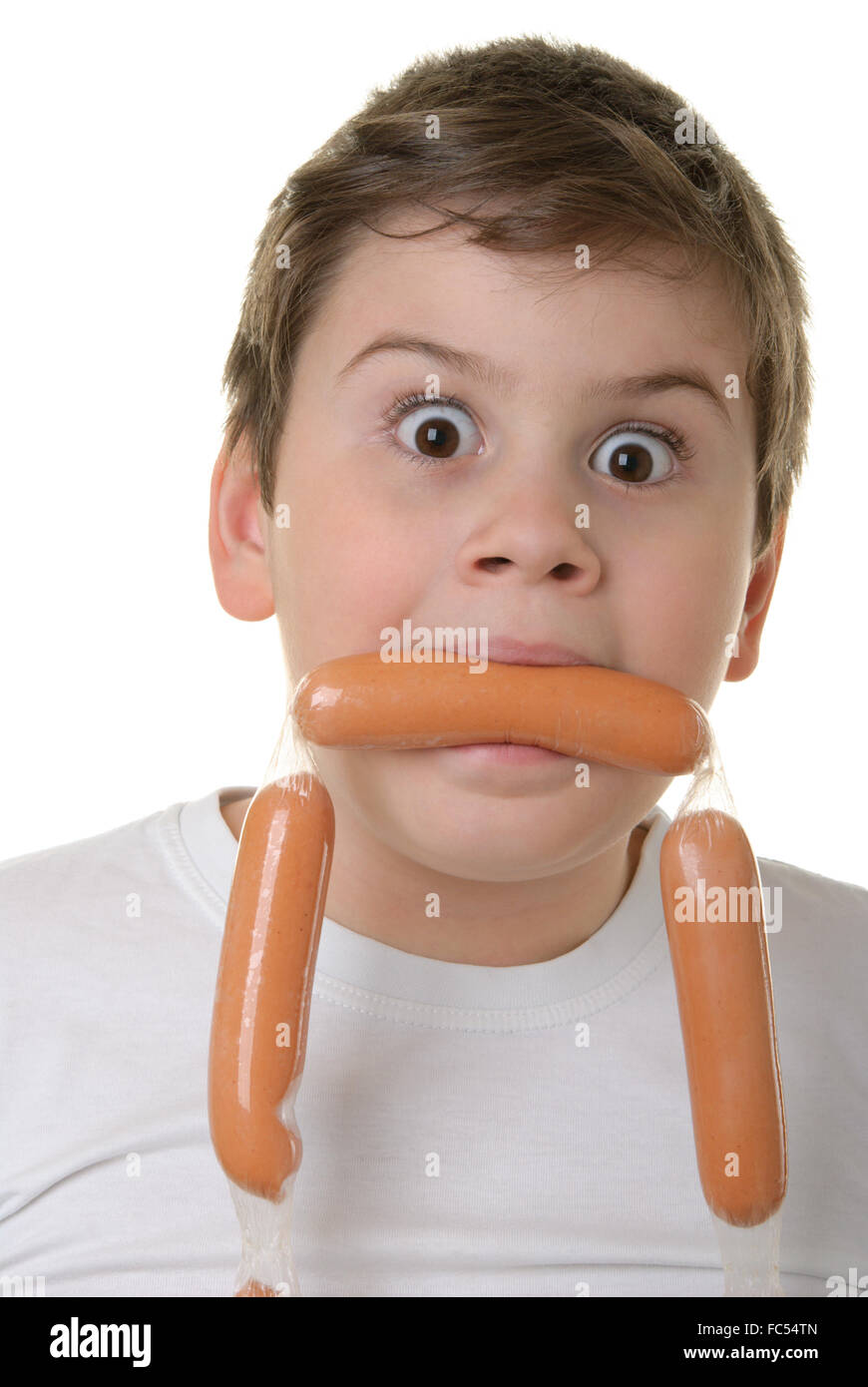 Surprised boy holds sausage in mouth Stock Photo