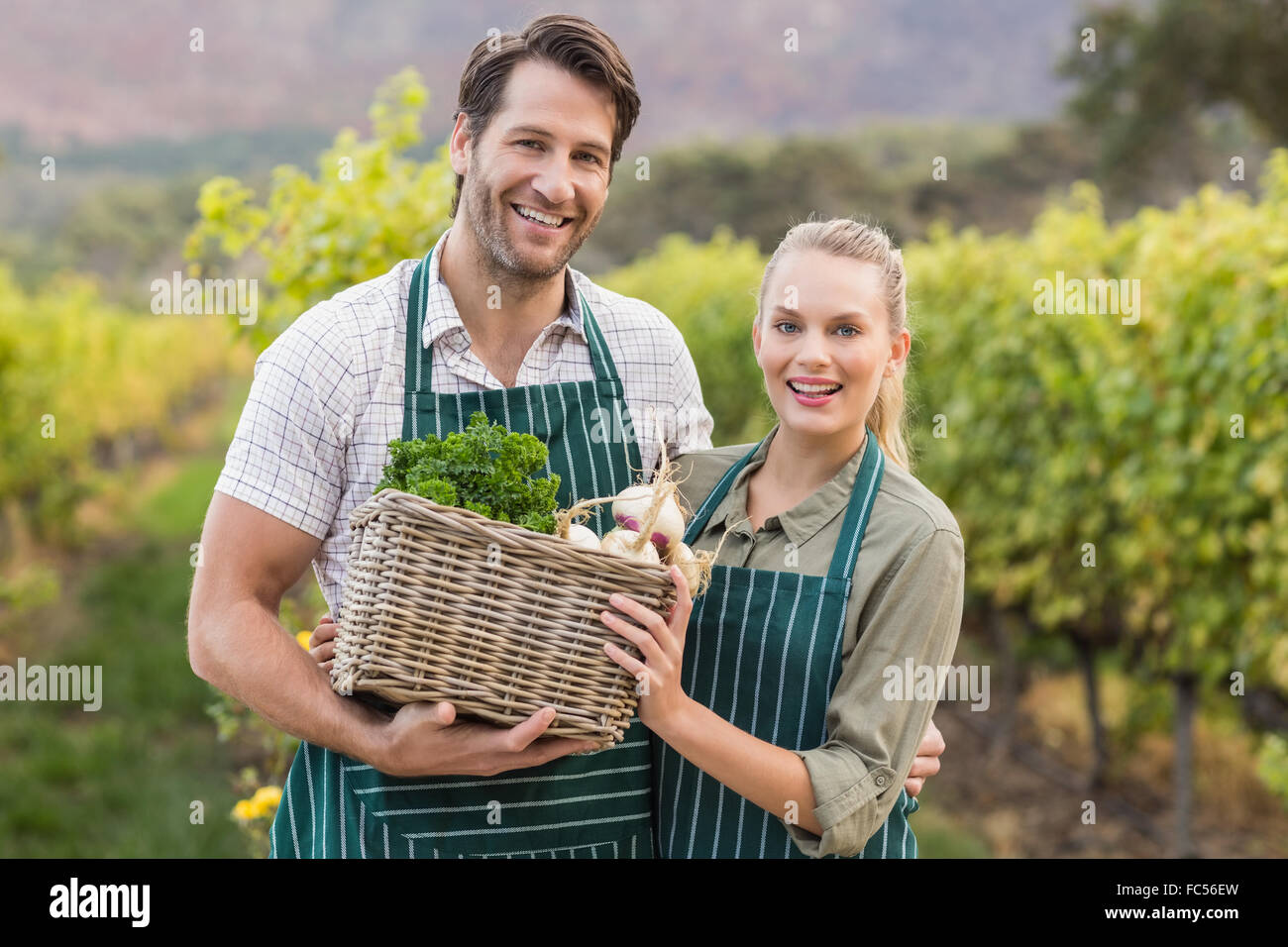 Two young happy farmers holding a basket of vegetables Stock Photo - Alamy