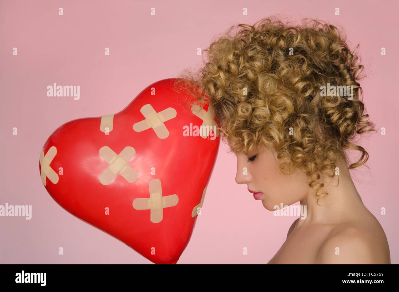 hurt woman with ball in shape of heart Stock Photo