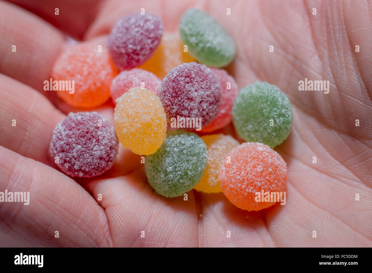 A serving (13 sweets) of jelly-tots held in the palm of a hand. Stock Photo