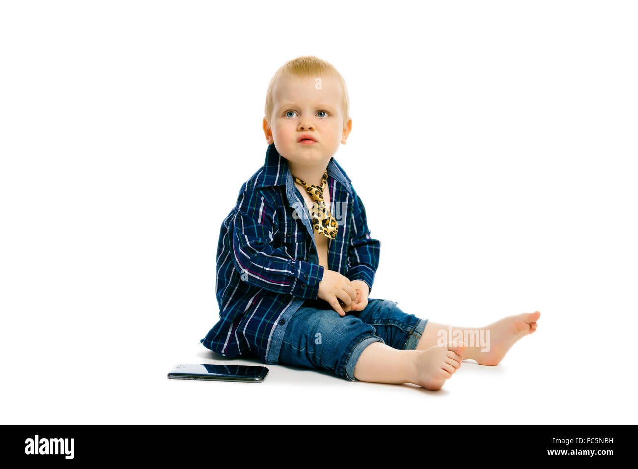 boy in a tie sitting on a white floor Stock Photo