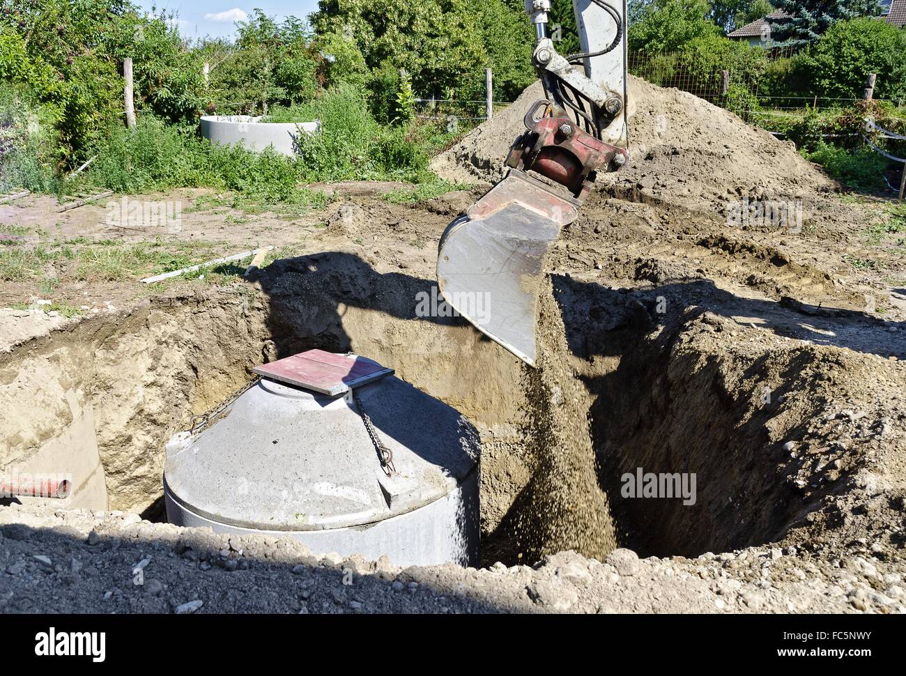 excavator pouring soil beside concrete rings Stock Photo