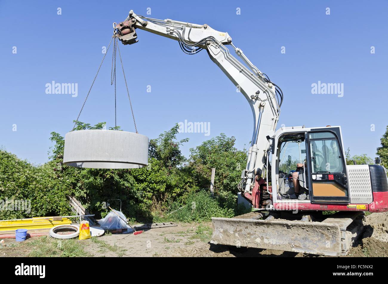 excavator llifting concrete ring Stock Photo