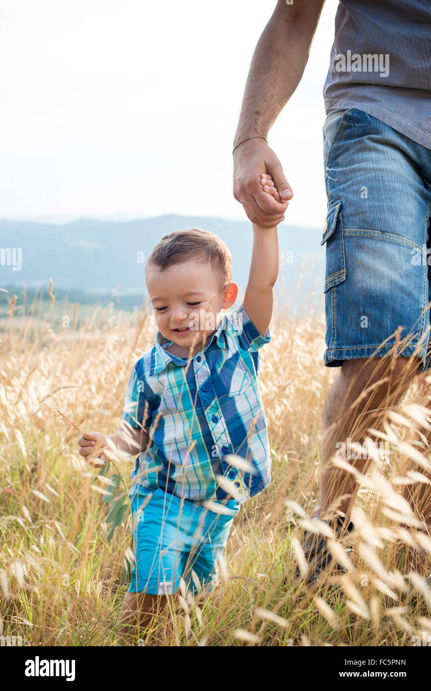 Man and Happy Young Boy Walking Through Field Stock Photo