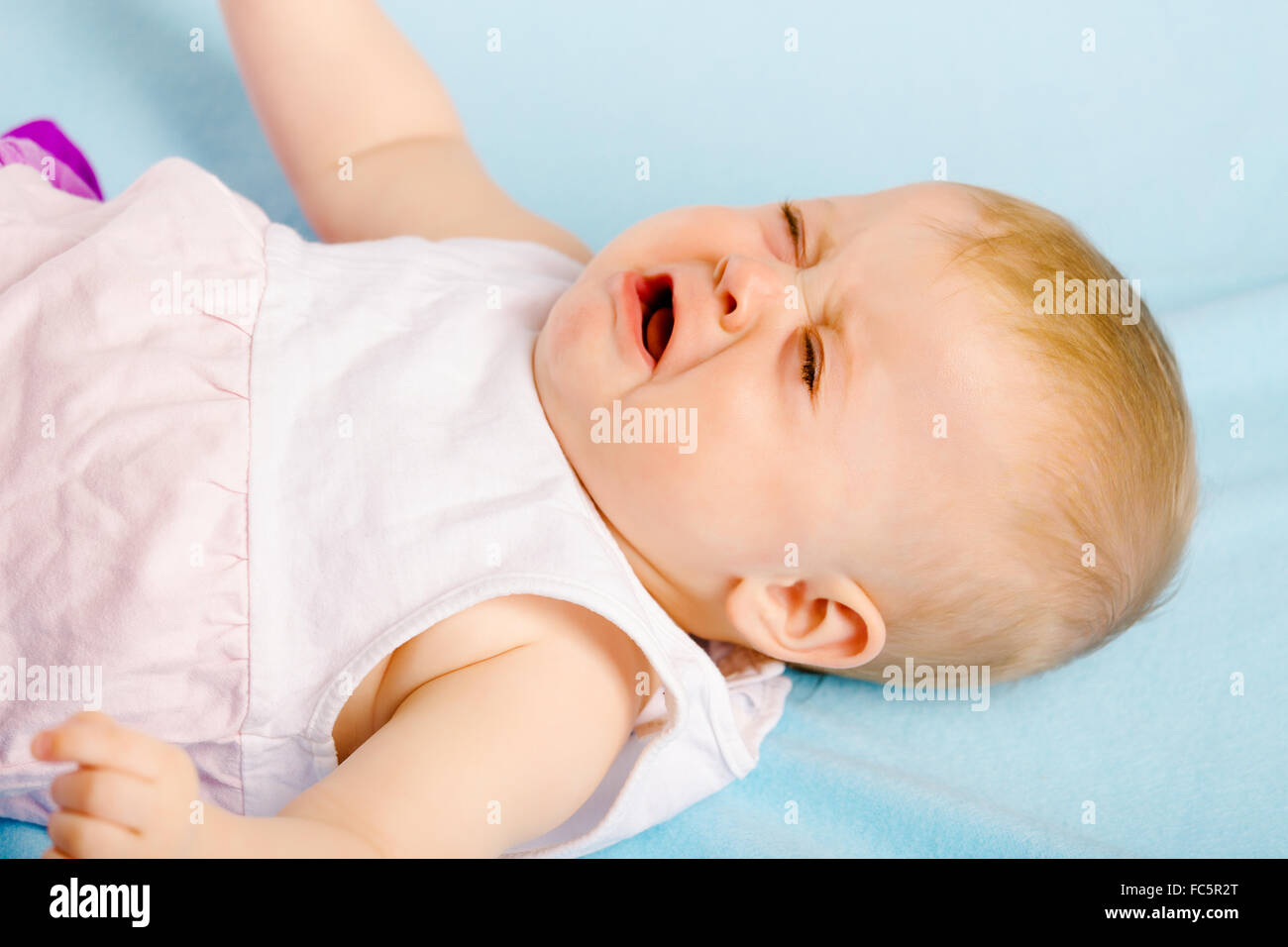 Crying baby lying on plaid Stock Photo