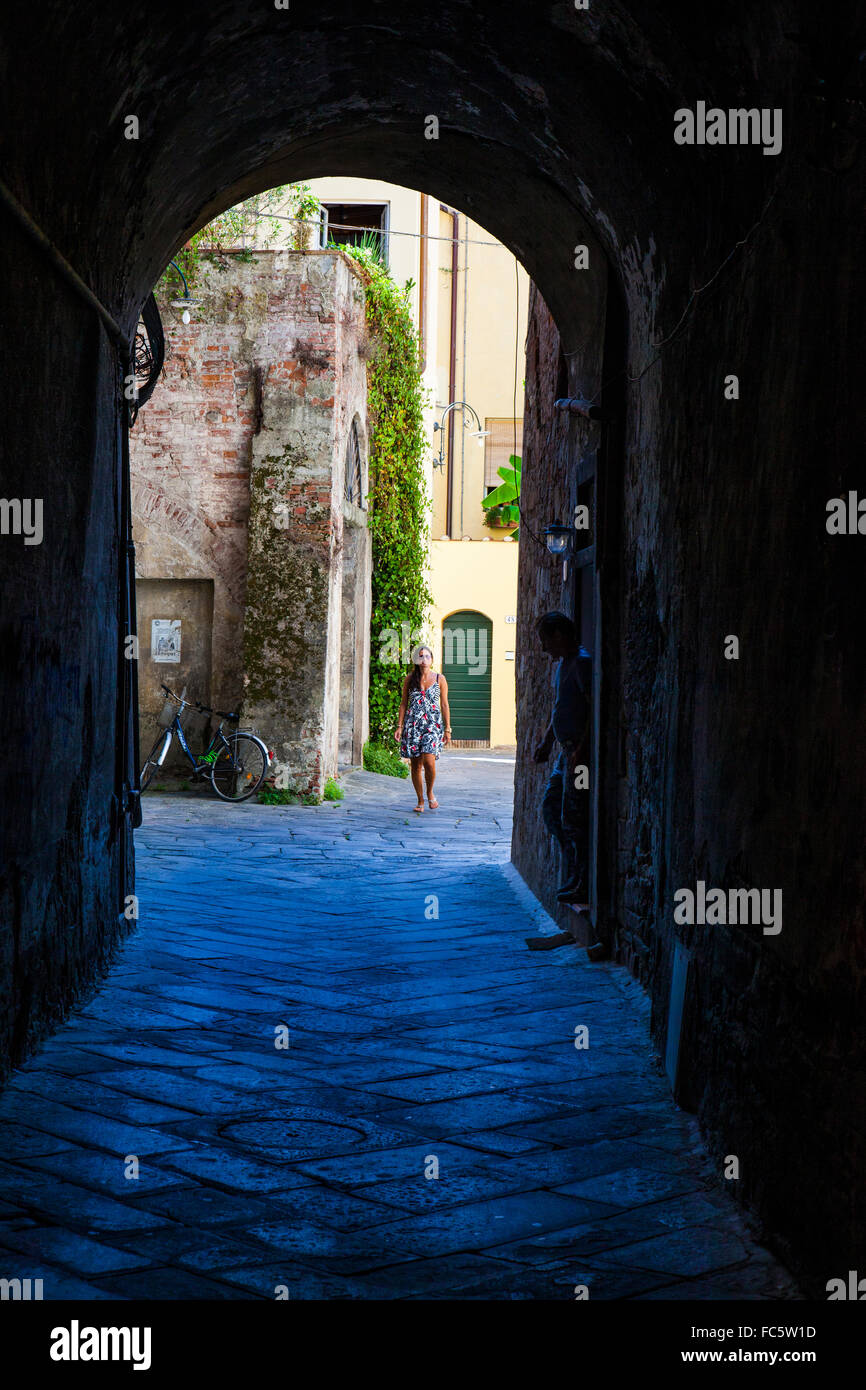Woman walking down an archway in Lucca, Tuscany, Italy. Stock Photo
