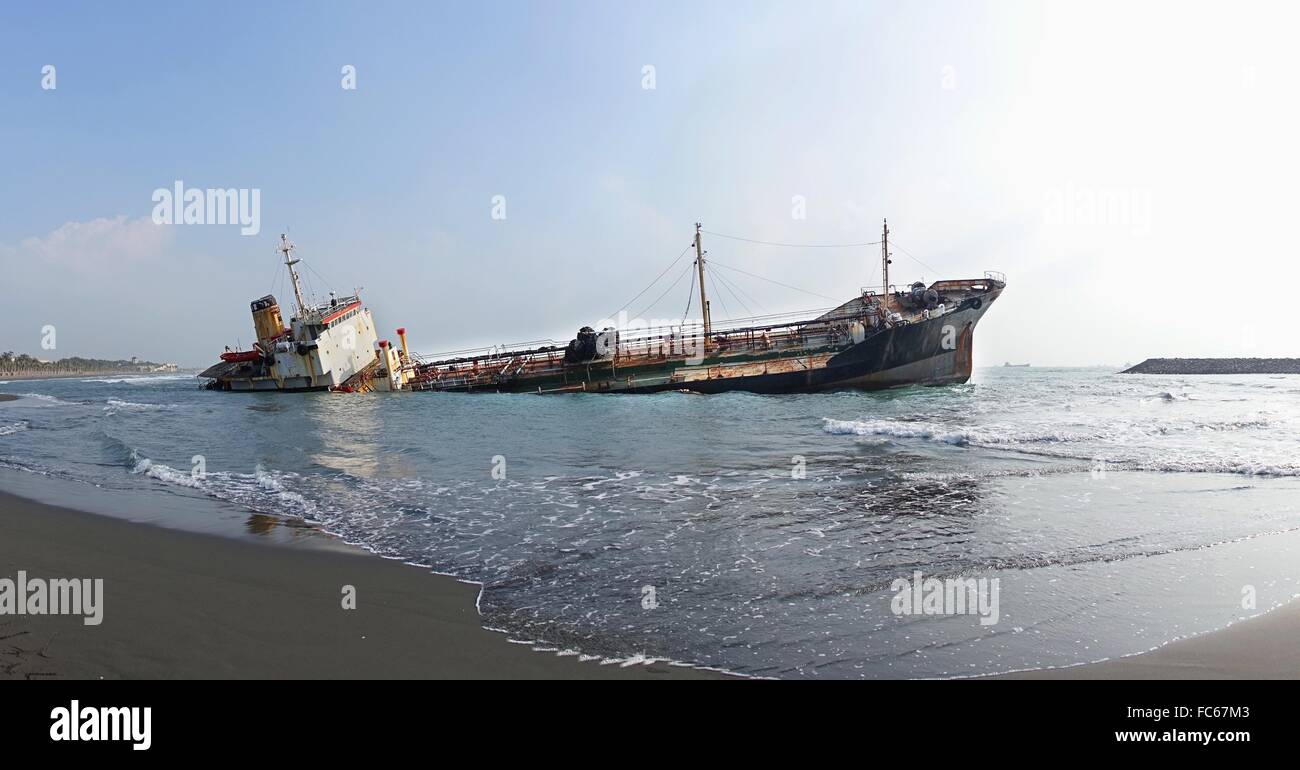 A ship has run aground in shallow waters and is sinking Stock Photo