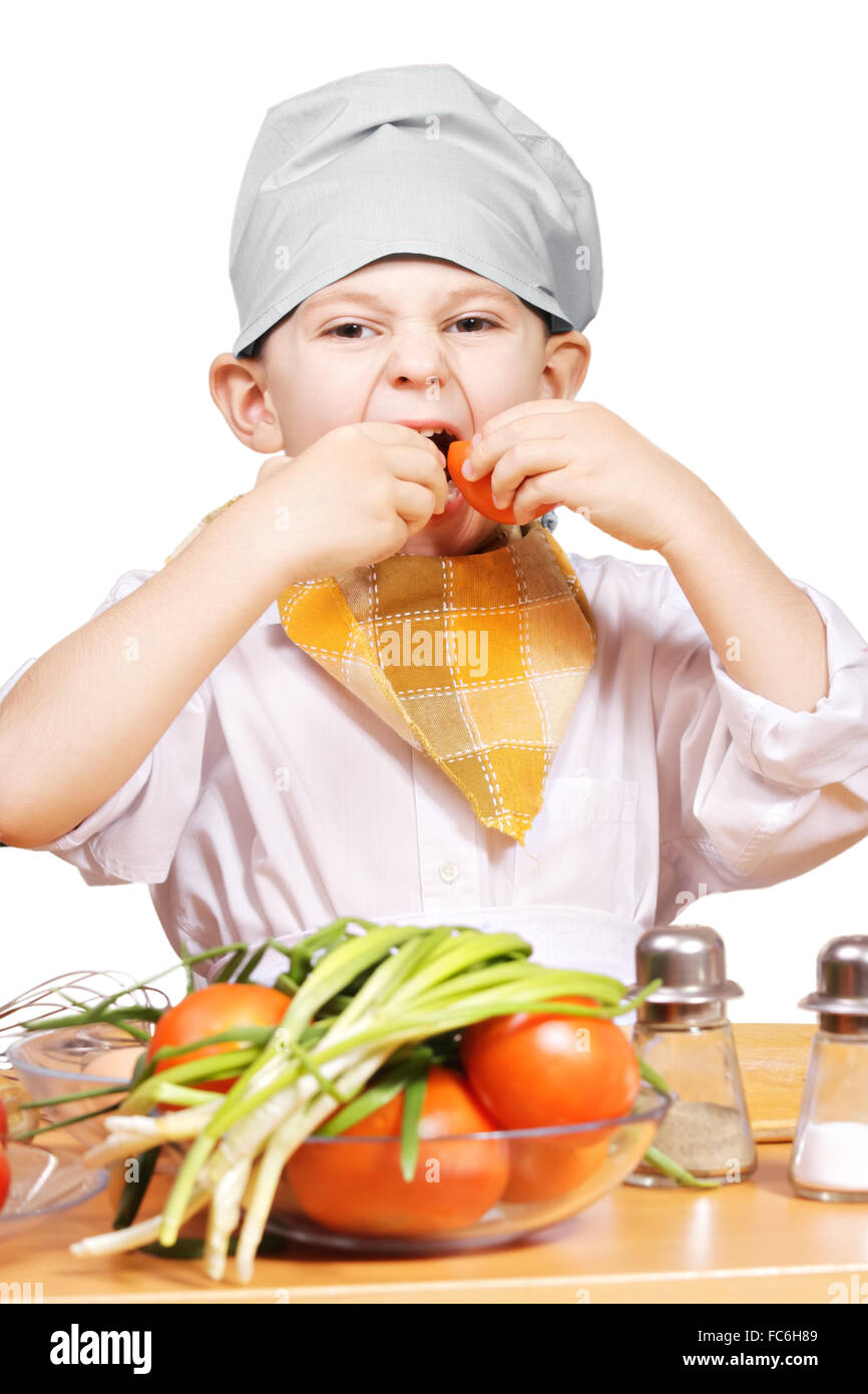 Funny little cook eating tomatoes Stock Photo