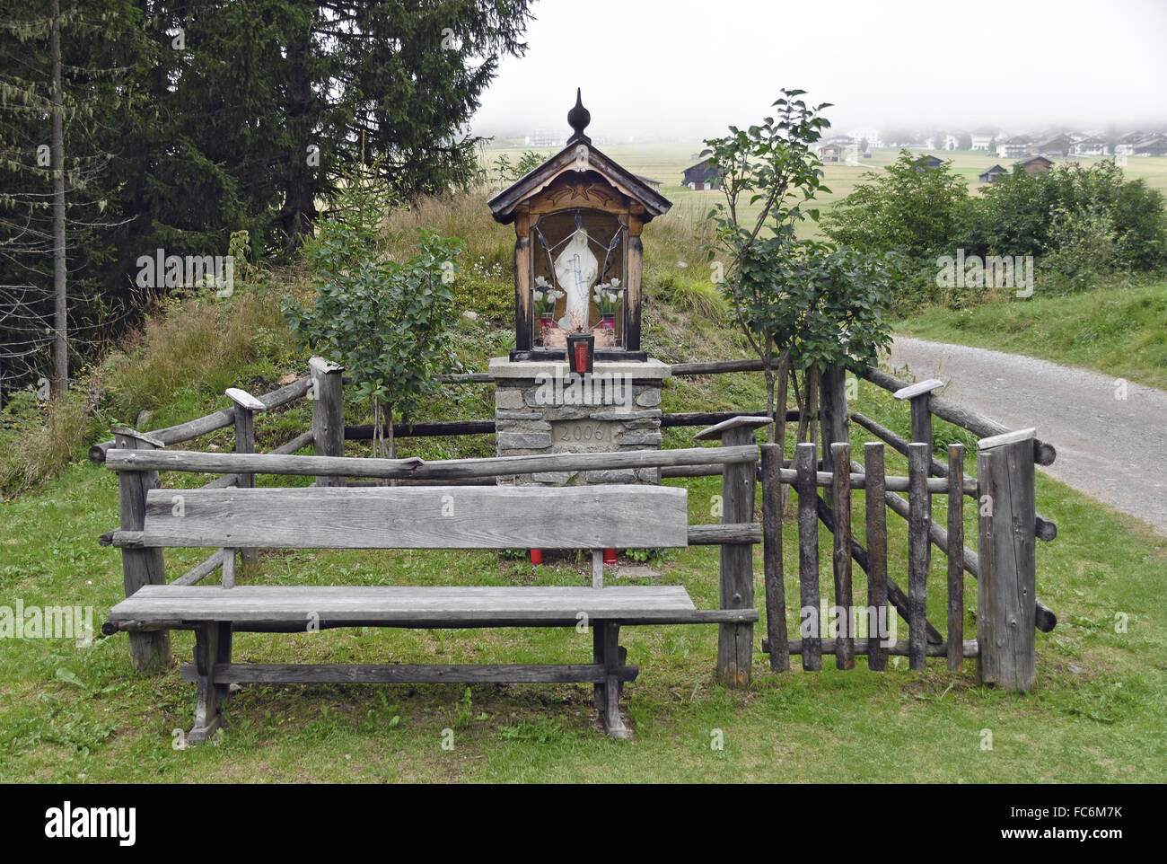 wayside shrine with wooden fence and bench Stock Photo