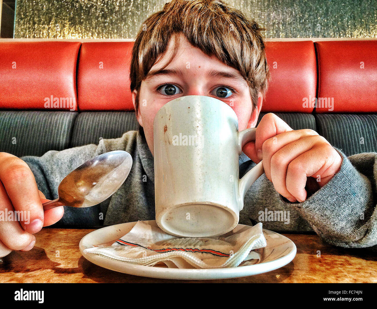 Caucasian boy drinking coffee in diner - Smartphone Captured Stock Image