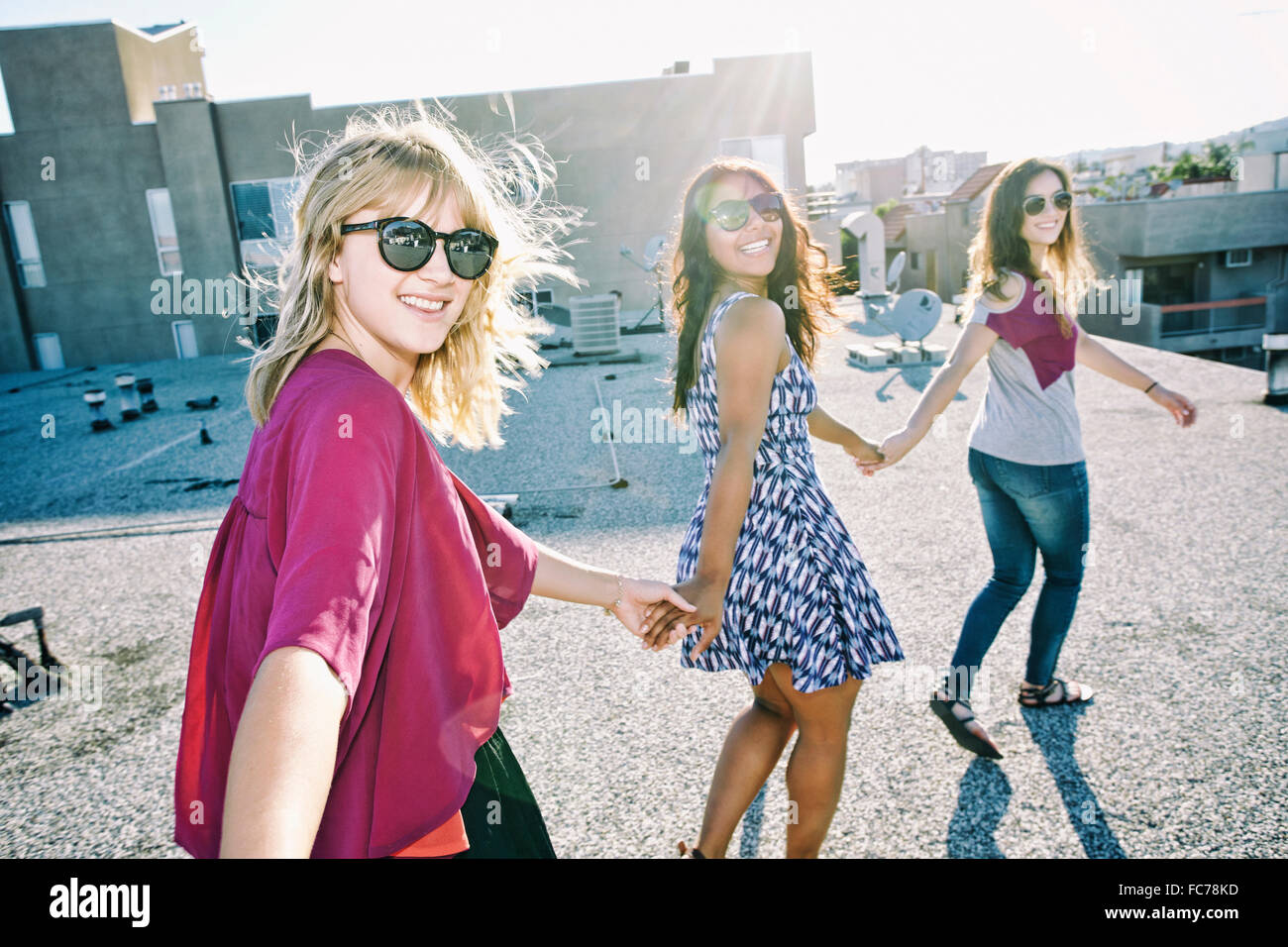 Women holding hands on urban rooftop Stock Photo