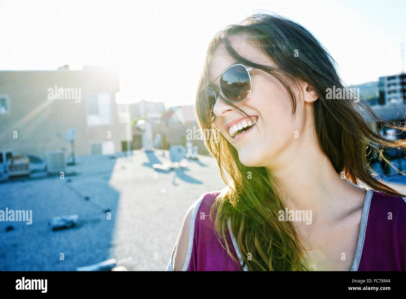 Mixed race woman smiling on urban rooftop Stock Photo