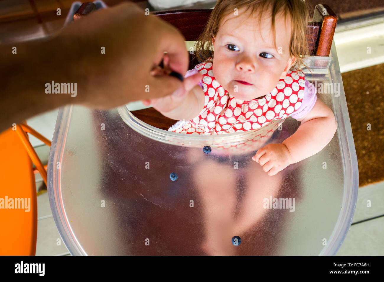 Father feeding baby girl in high chair Stock Photo