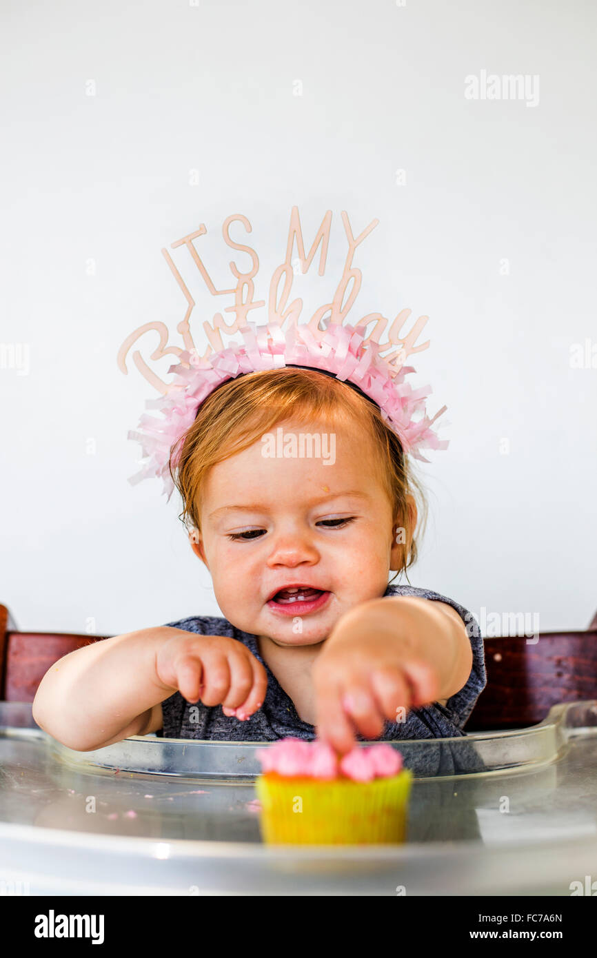 Caucasian baby girl eating birthday cupcake Stock Photo