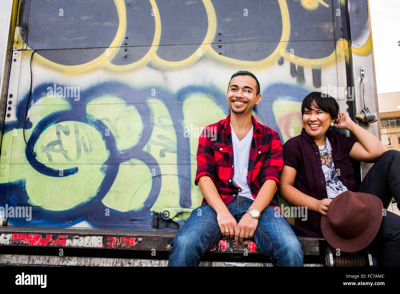 Couple sitting on graffiti truck Stock Photo