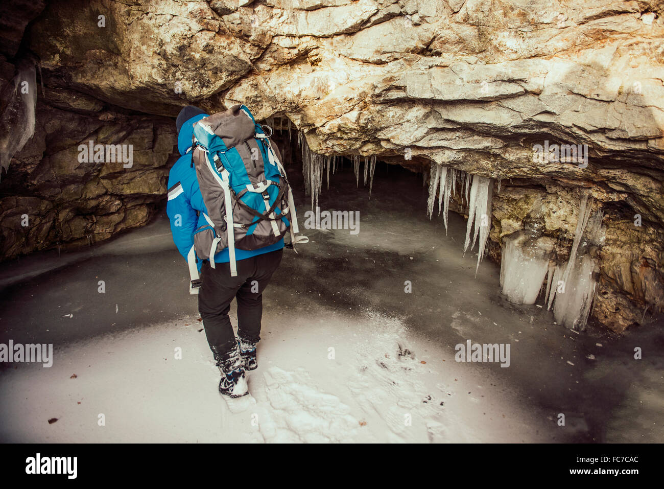 Caucasian woman exploring stalactites in cave Stock Photo
