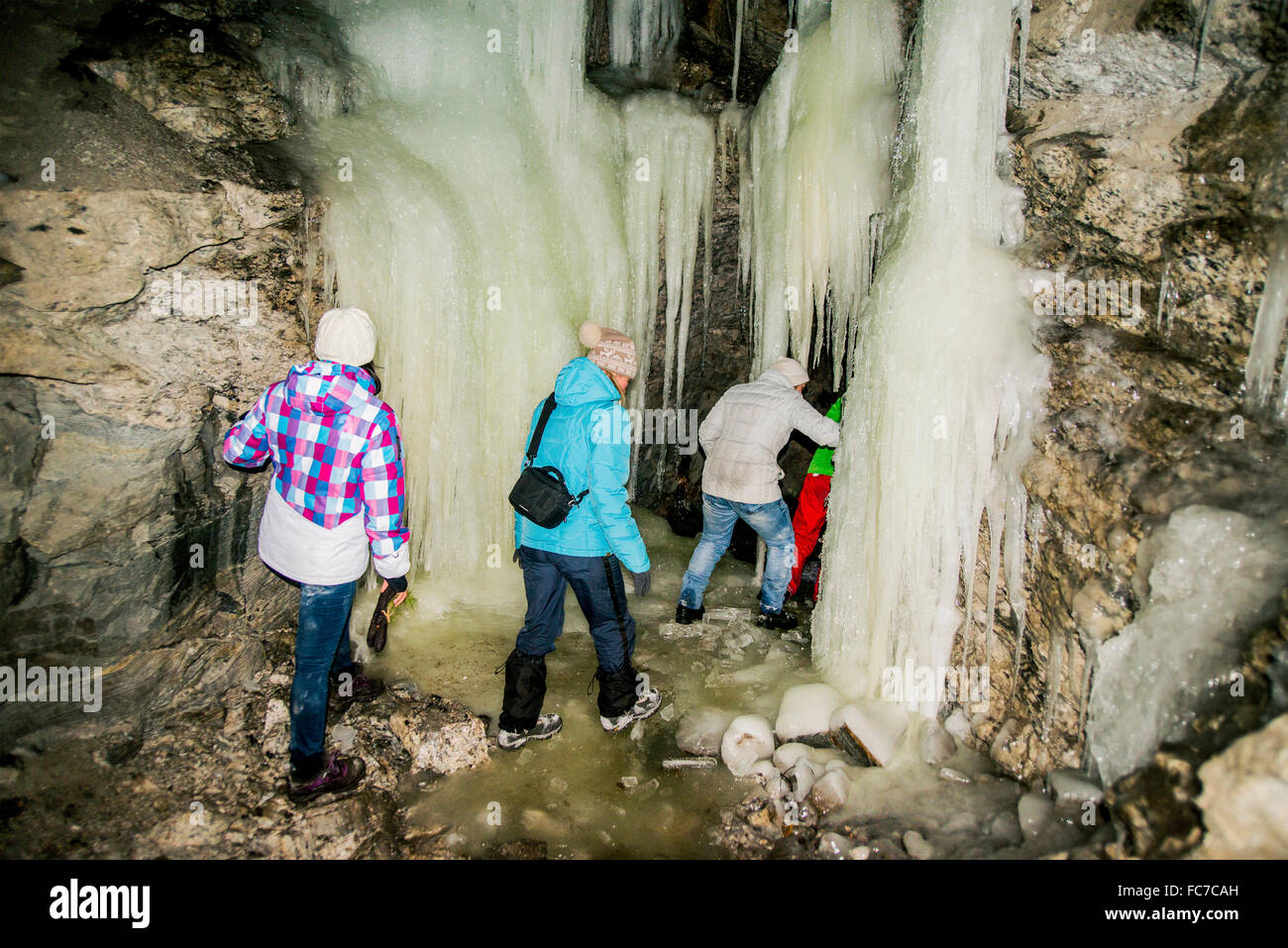 Caucasian hikers exploring stalactite cave Stock Photo