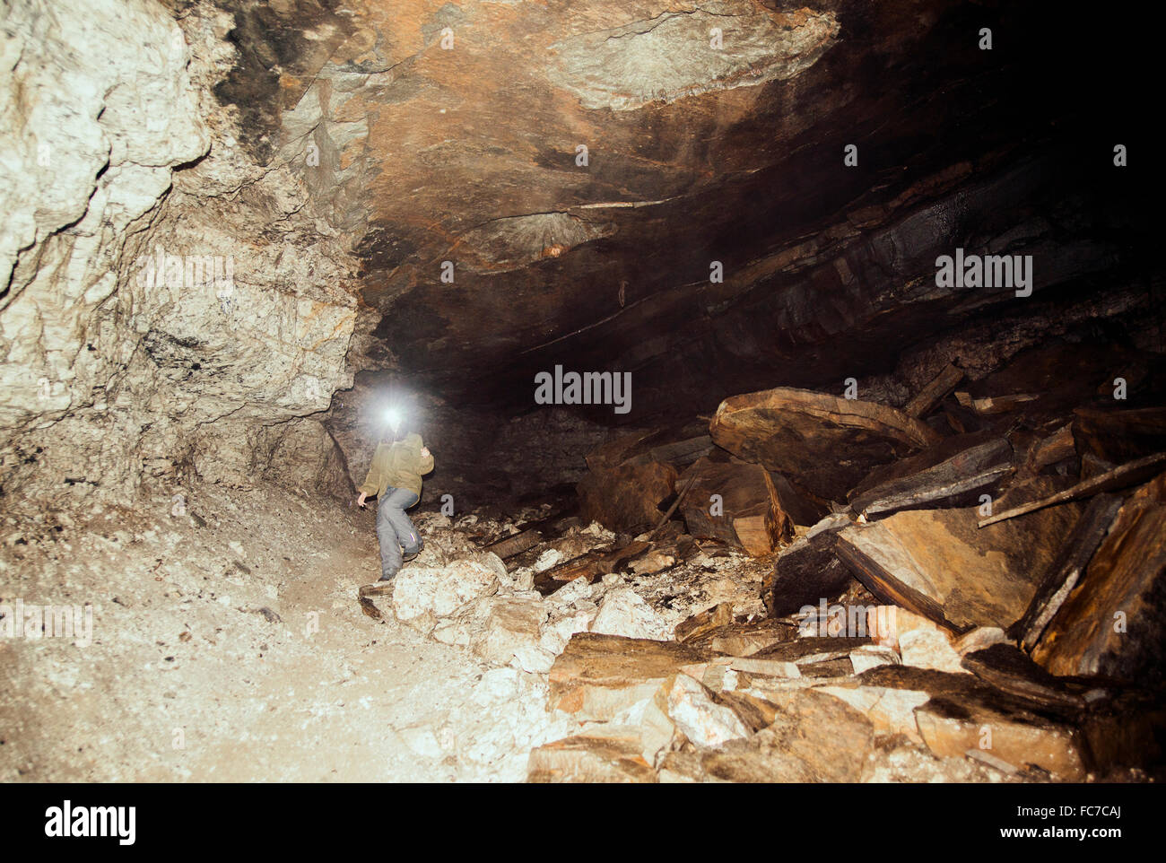 Caucasian hiker wearing headlamp in cave Stock Photo