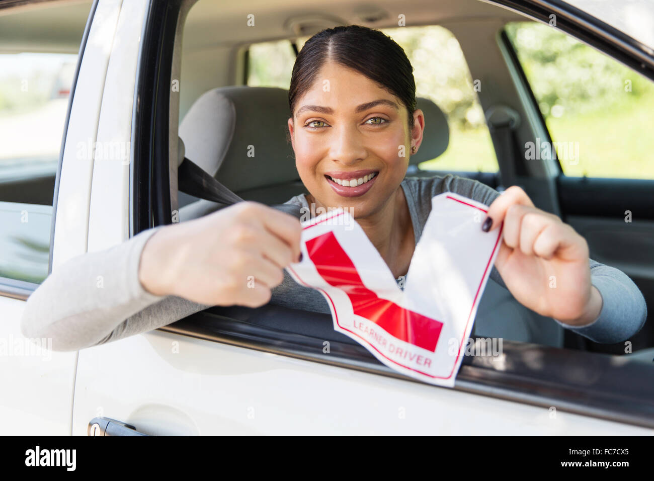 happy female driver tearing up her learner driver sign Stock Photo