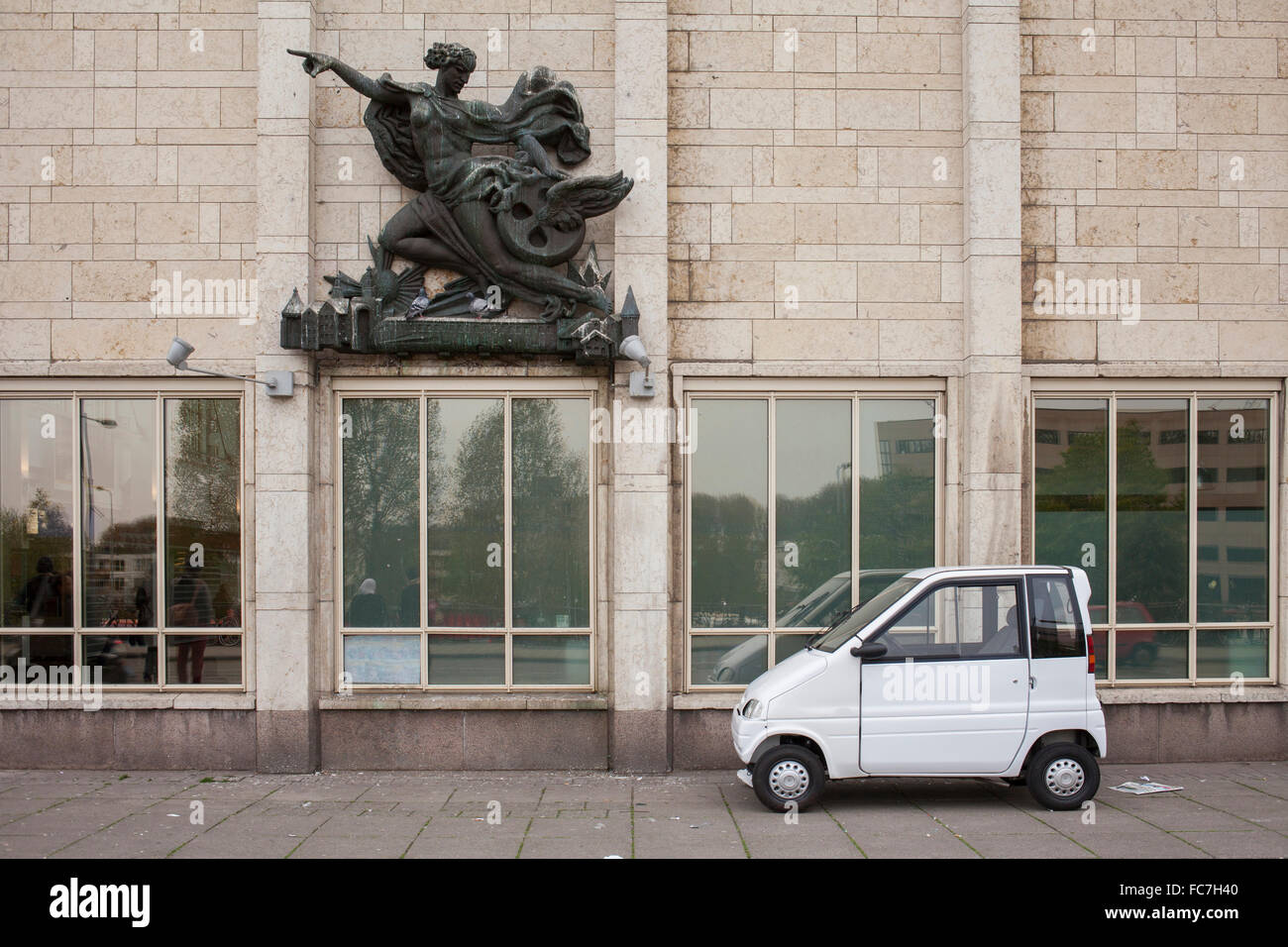Compact car parked under sculpture on building Stock Photo