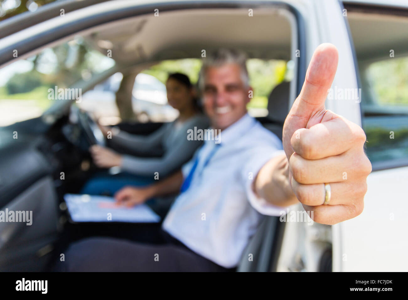 driving school instructor with learner driver giving thumb up Stock Photo