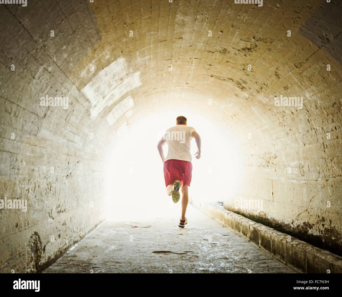 Caucasian man jogging in tunnel Stock Photo