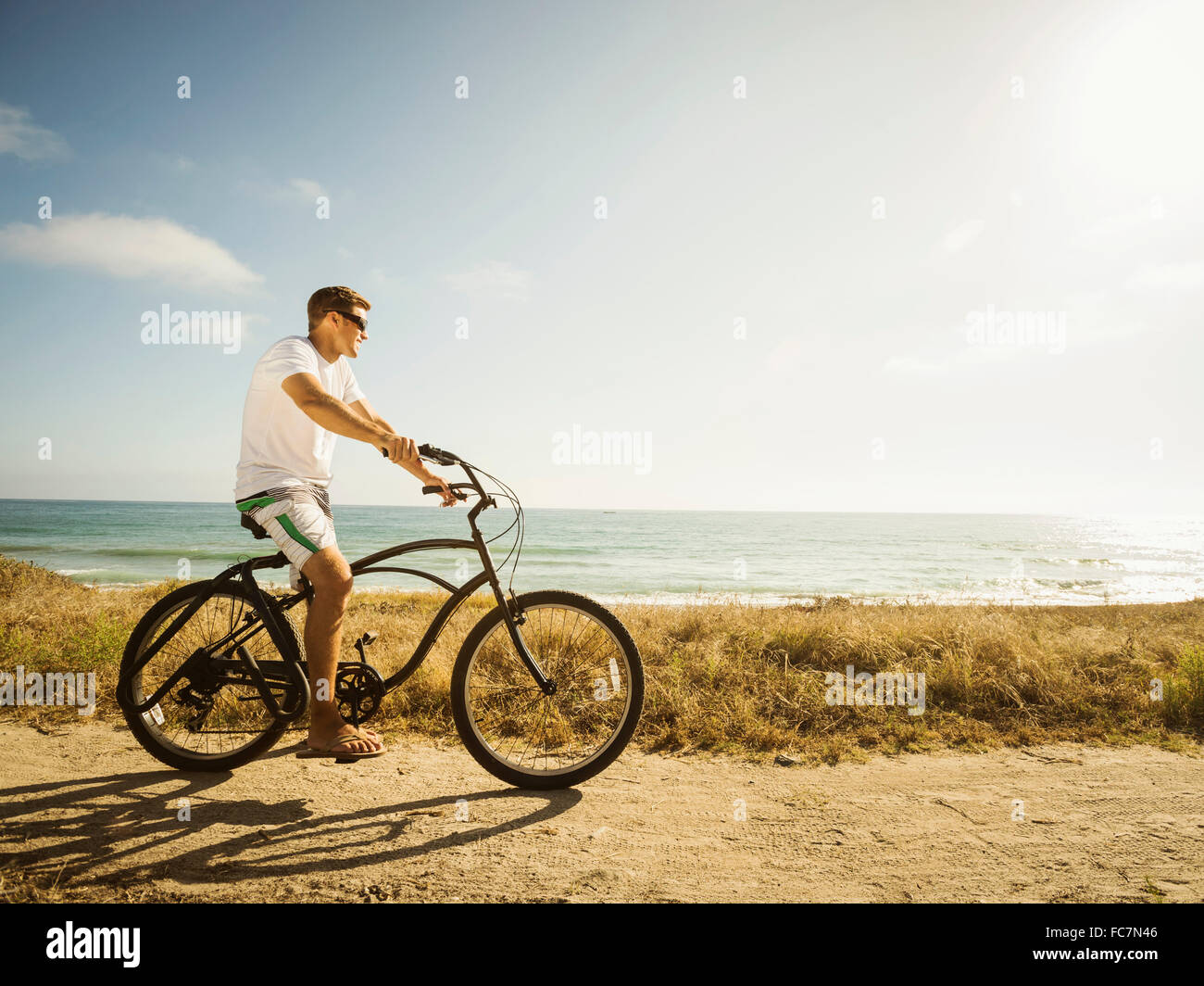 Caucasian man riding bicycle on beach Stock Photo