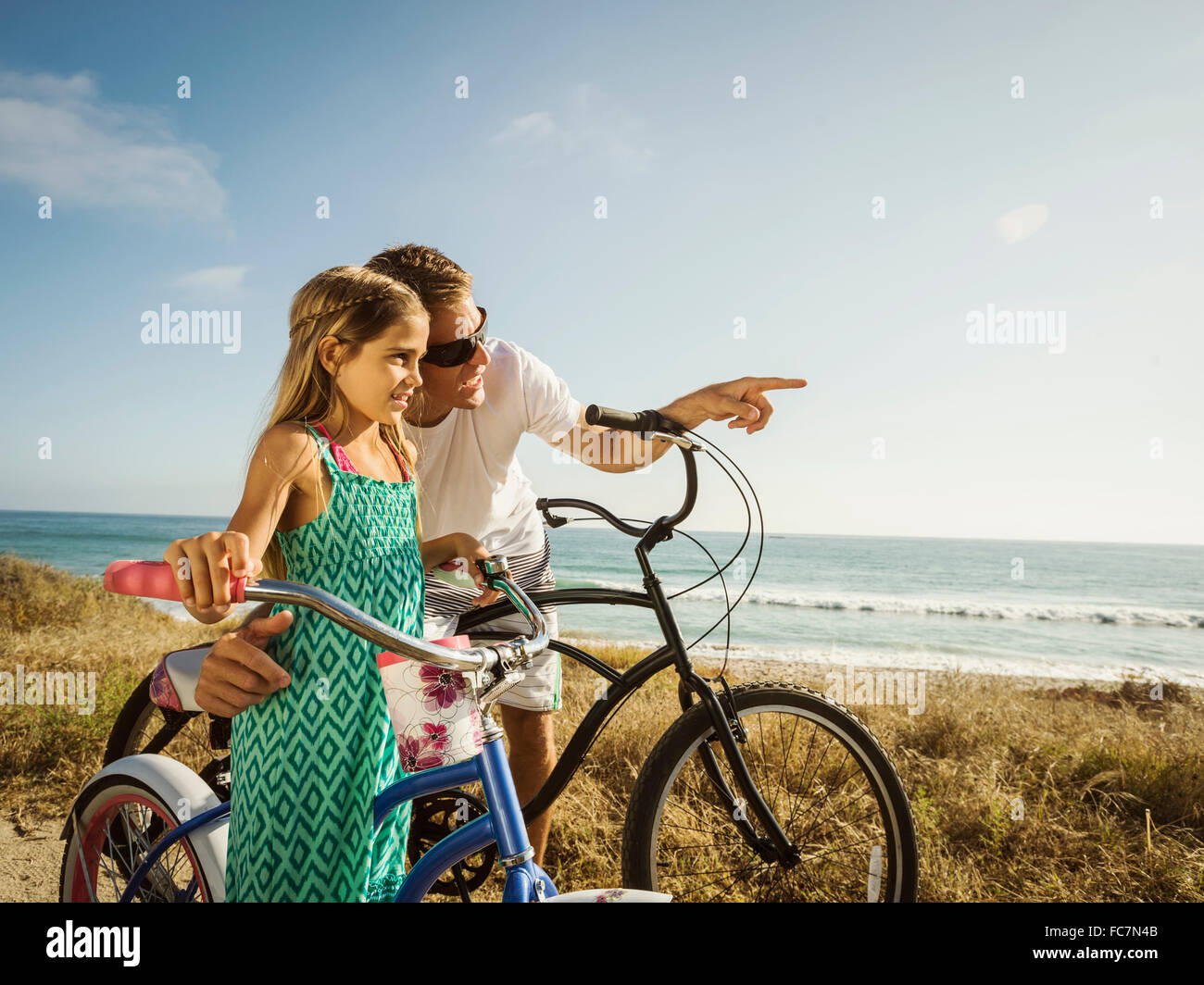 Caucasian father and daughter riding bicycles on beach Stock Photo