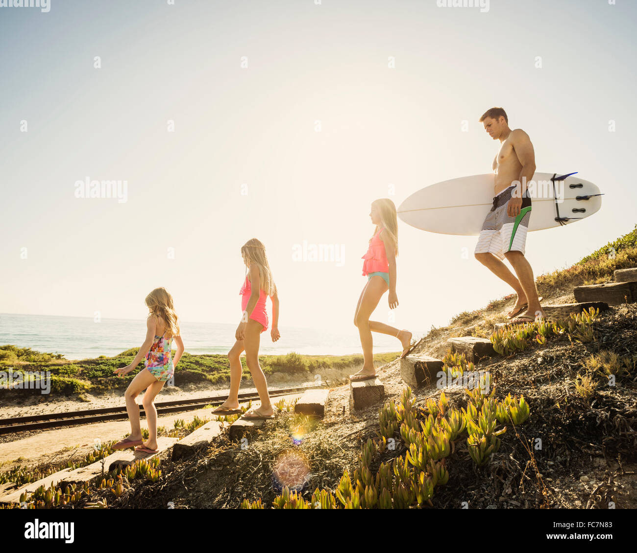 Caucasian father and daughters walking on beach Stock Photo