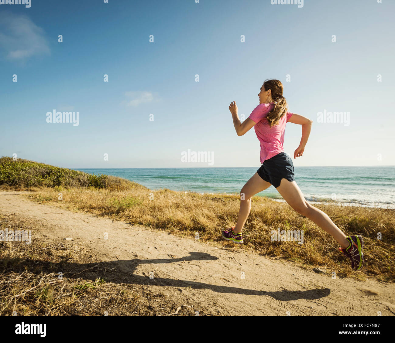 Caucasian woman jogging on beach Stock Photo
