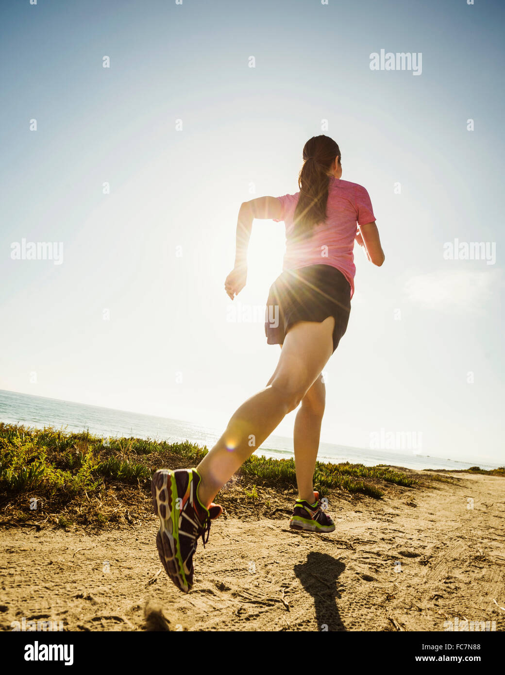 Caucasian woman jogging on dirt path Stock Photo