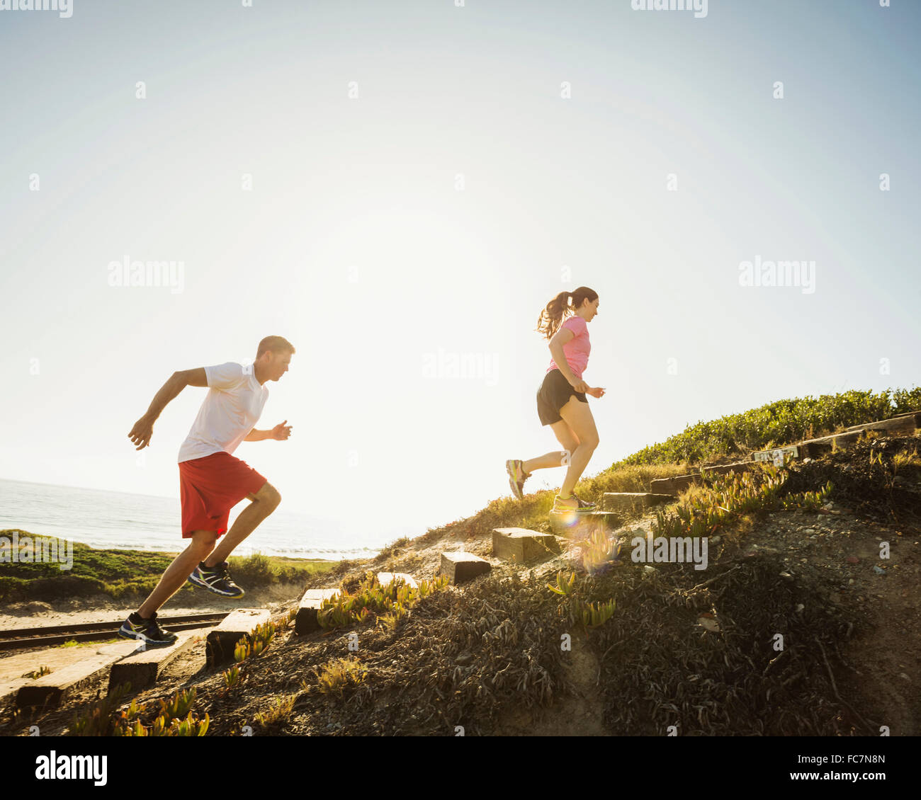 Caucasian couple jogging uphill Stock Photo