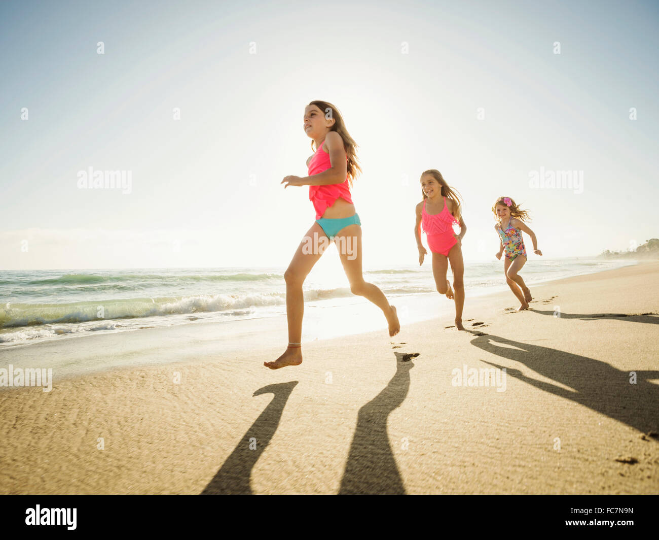 Caucasian sisters running on beach Stock Photo