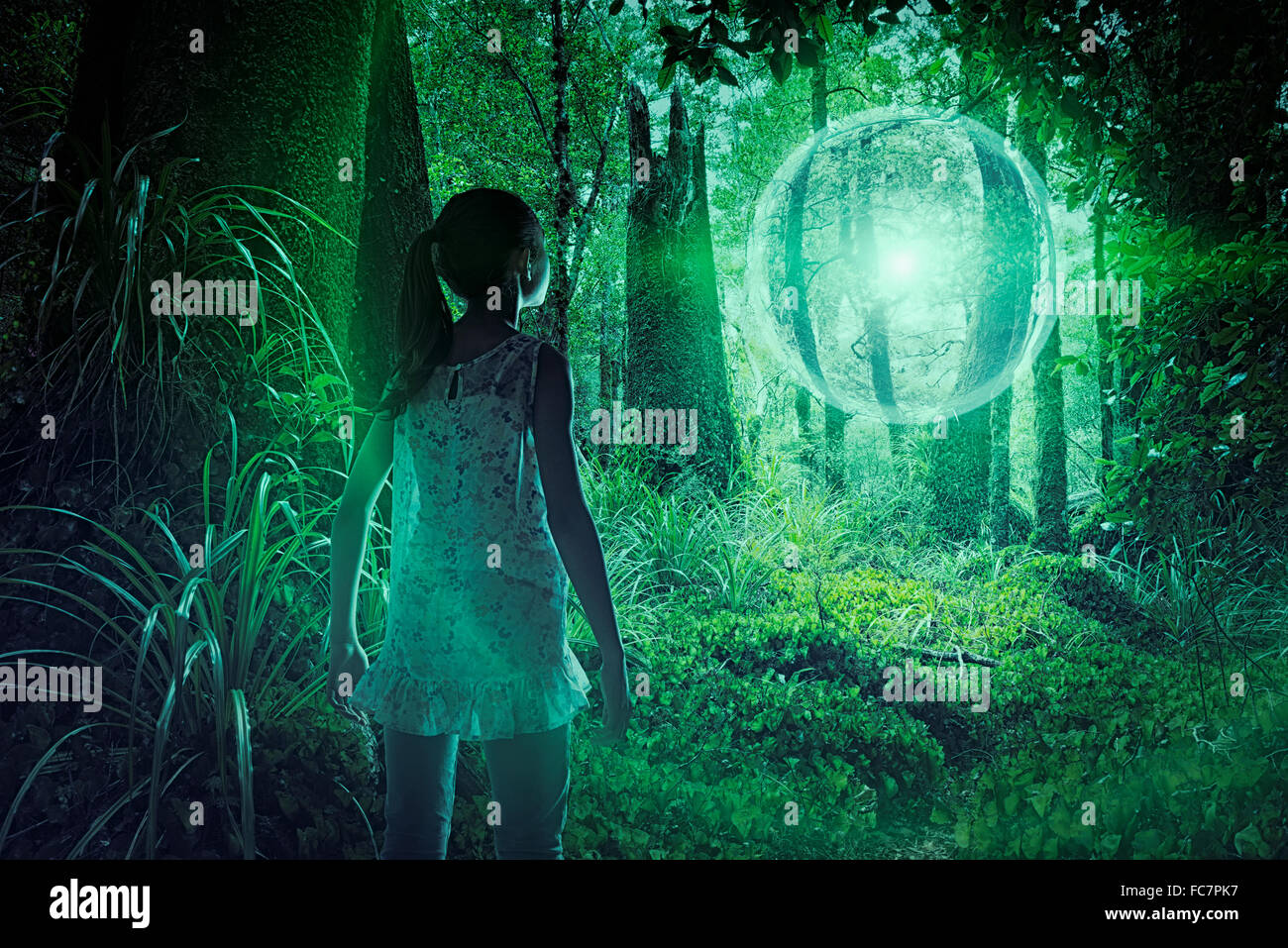 Mixed race girl discovering glowing sphere in forest Stock Photo