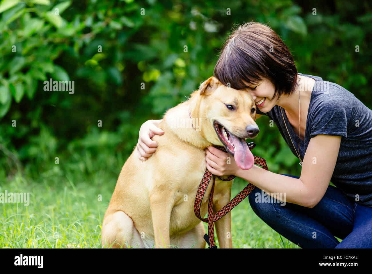 Caucasian woman petting dog in field Stock Photo