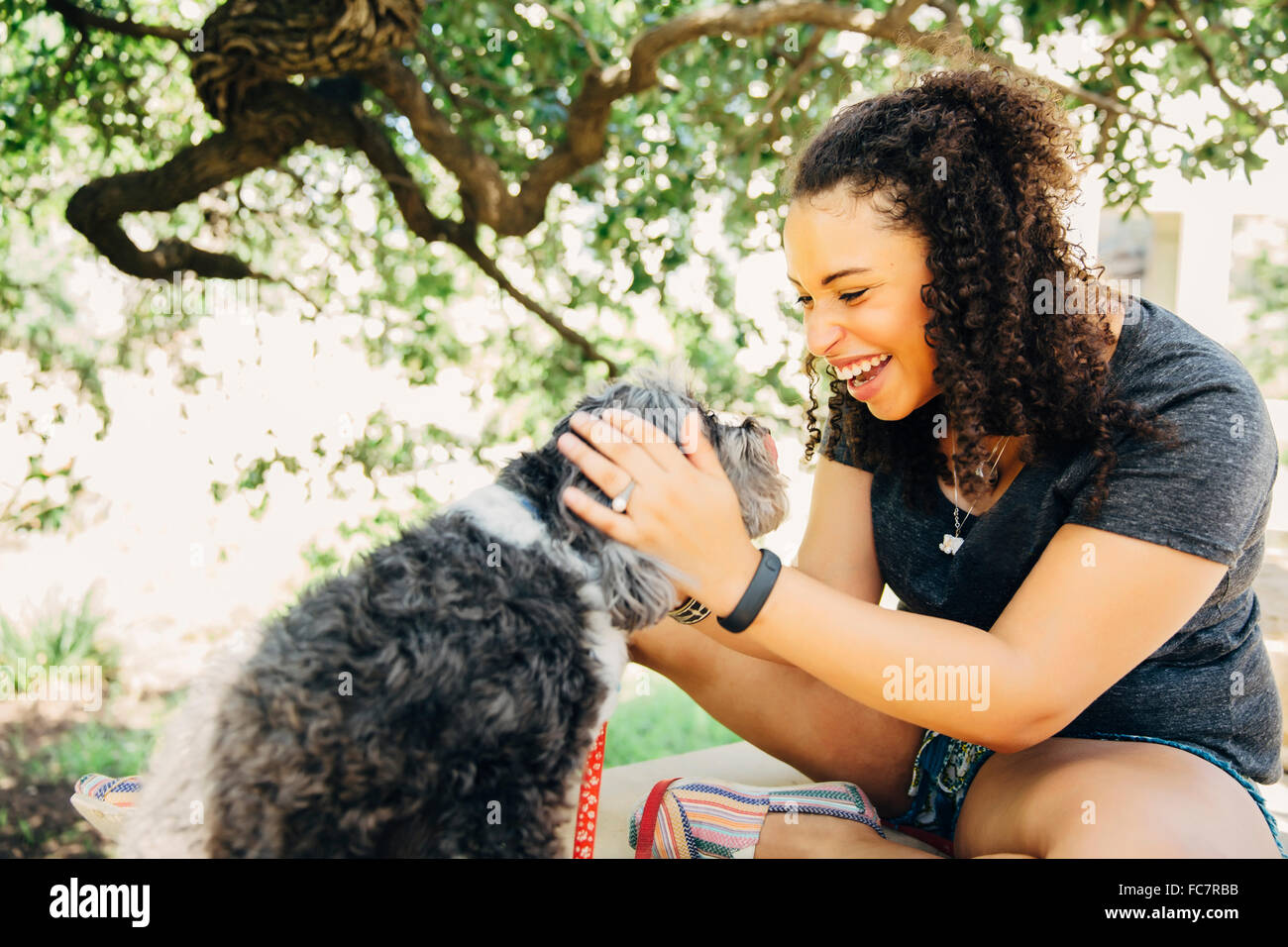 Black woman petting dog outdoors Stock Photo