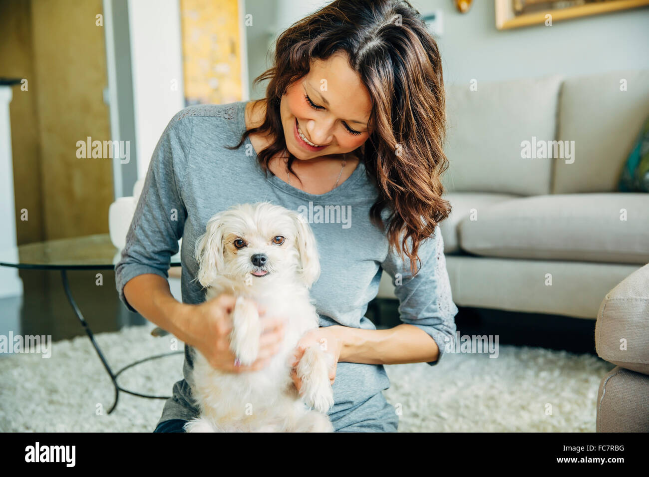 Caucasian woman petting dog in living room Stock Photo