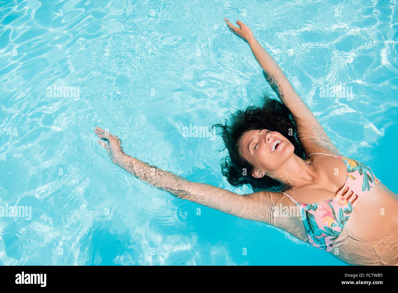 Caucasian woman floating in swimming pool Stock Photo